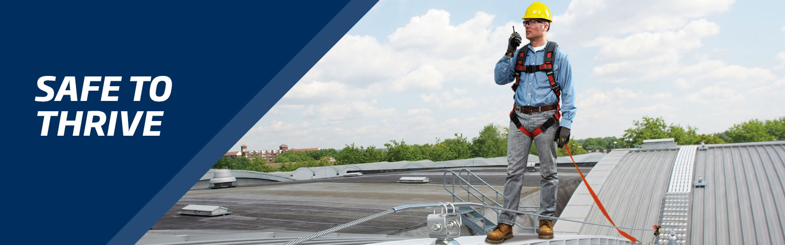 Fall protection consulting page banner - A man with safety equipment for working at heights stands on a roof radio communicating with his team.